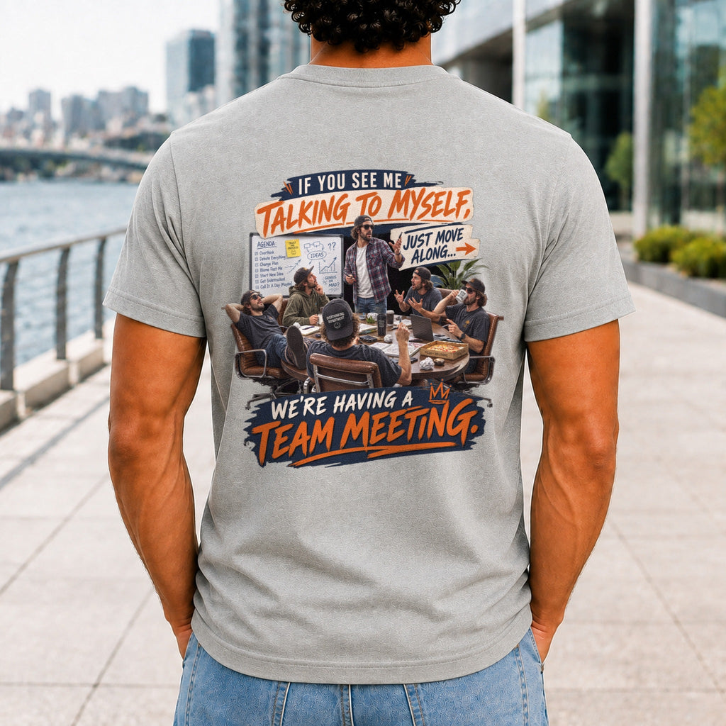 We're Having A Team Meeting graphic printed on the back of an athletic heather KRED Threads premium tee