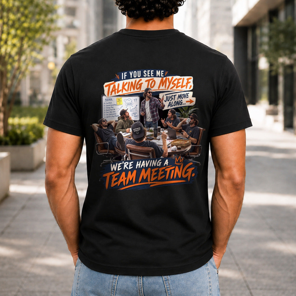 We're Having A Team Meeting graphic printed on the back of a black KRED Threads premium tee