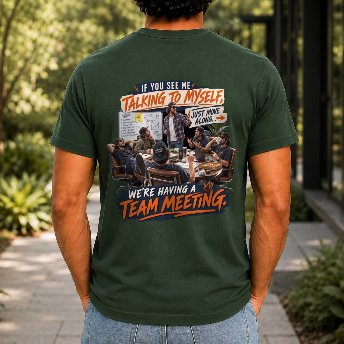 We're Having A Team Meeting graphic printed on the back of a forest green KRED Threads premium tee