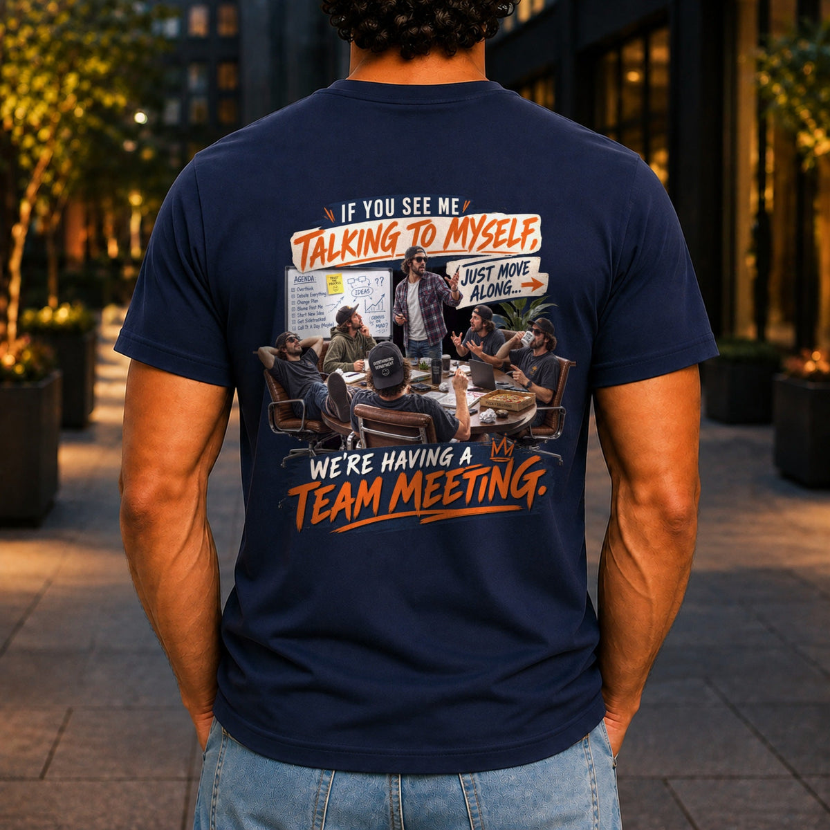 We're Having A Team Meeting graphic printed on the back of a navy KRED Threads premium tee