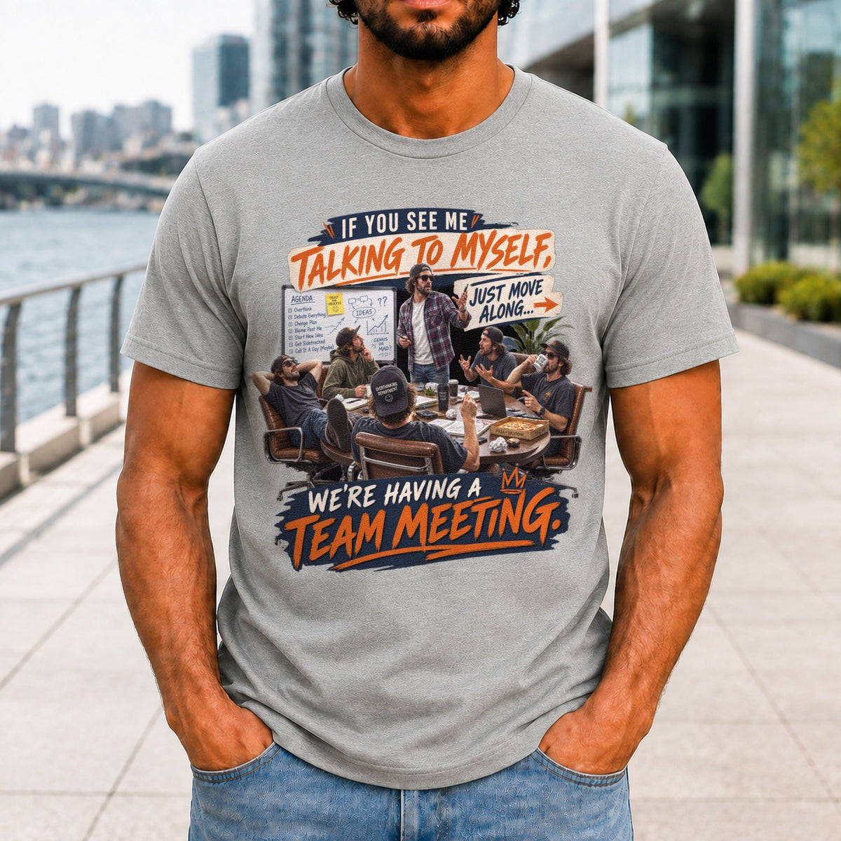 We're Having A Team Meeting graphic printed on the front of an athletic heather KRED Threads premium tee