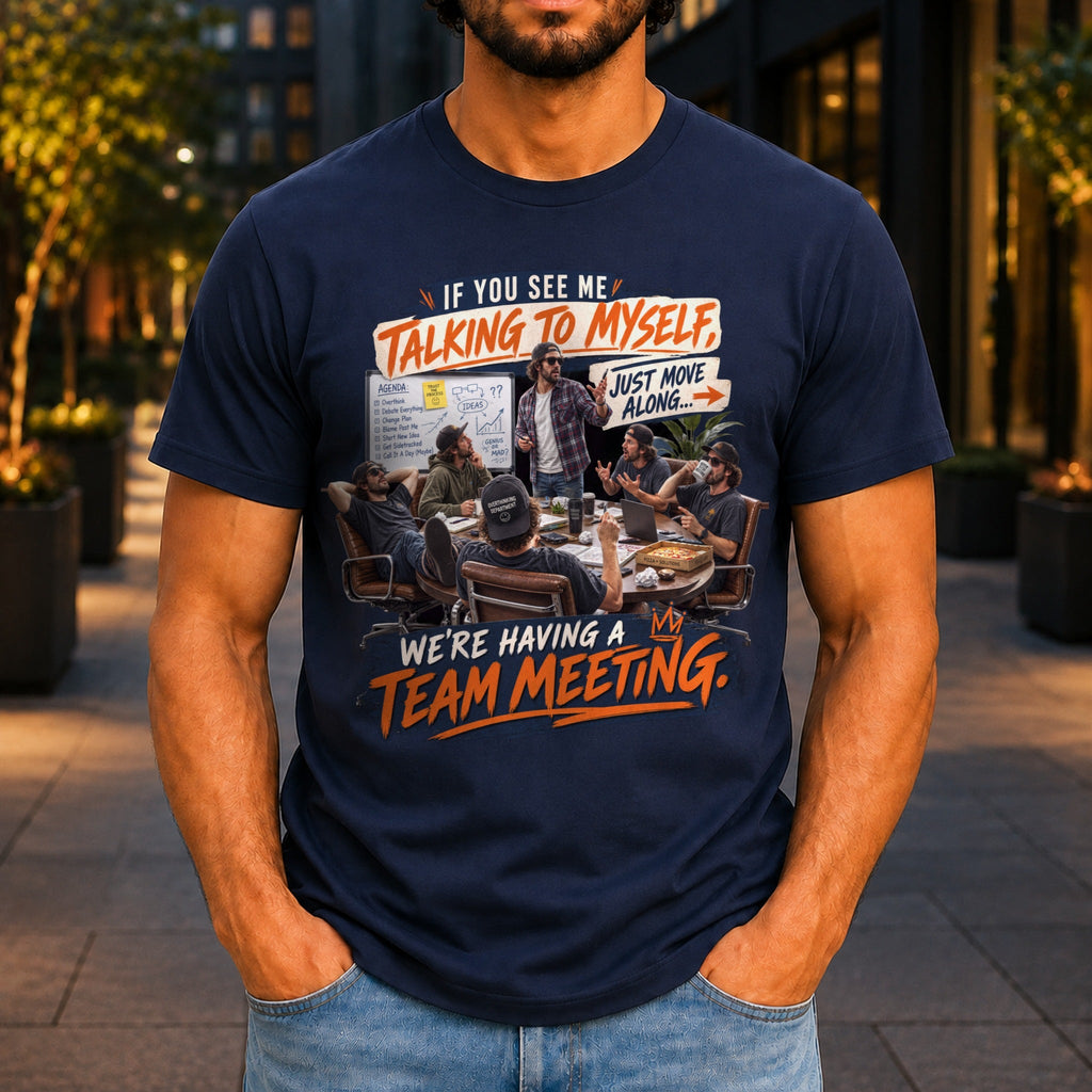 We're Having A Team Meeting graphic printed on the front of a navy KRED Threads premium tee